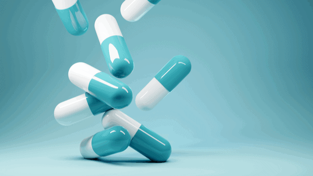 A 3D-graphic rendering of blue and white pills against a blue background